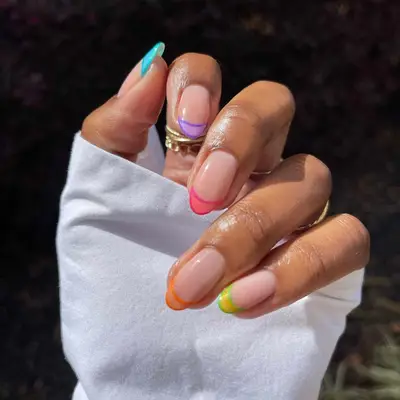 A two-tone French manicure in shades of blue, purple, pink, orange, and yellow/green