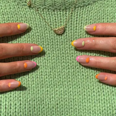 Mismatched French mani in bright summer colors held against green sweater