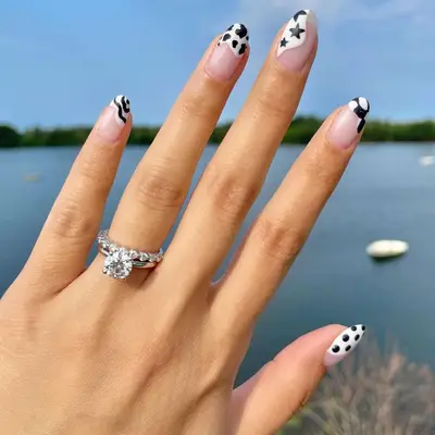 A manicure with black and white nail art on the tips, and a clear base