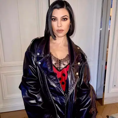Kourtney Kardashian wering a red dress and leather jacket 