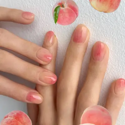 Hands with peach-themed nail art against a white background, peach illustrations surround the scene