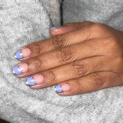 Nude nails with a periwinkle french tip outlined in silver