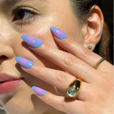 Close-up of woman holding periwinkle and purple aura manicure by her face