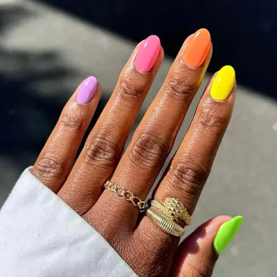 Colorful skittle nails with a purple, pink, orange, yellow, and green nail