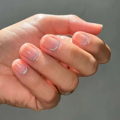 Close up of a manicure with silver glitter semi-circles at the cuticles