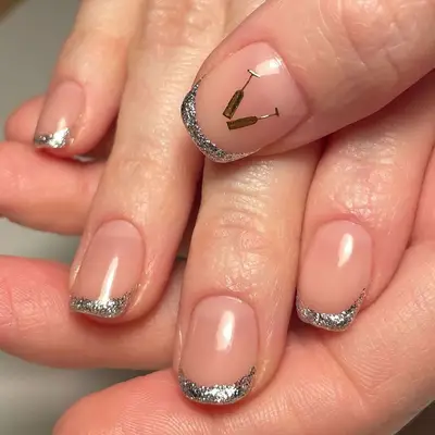 Close up of a manicure with silver French tips and champagne glass decals