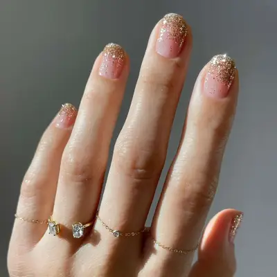 Close up of a short manicure with gold glittery tips