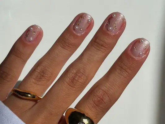 A shimmery manicure with pearl and gold foil accents