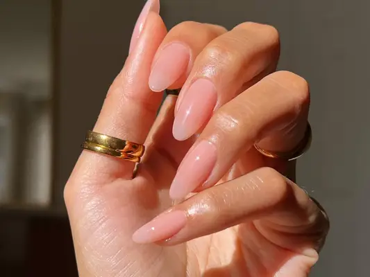 Close up of a long oval manicure in a nude-pink polish.