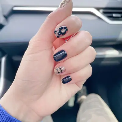 Black and gold mixed-pattern nails with smiley face and checkerboard designs
