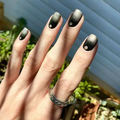 Black and gold ombre nails with gold dot near cuticle