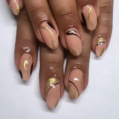Peachy beige manicure with swirling black and gold nail design