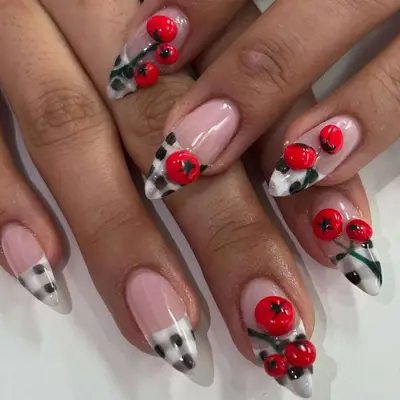Hands showing nails decorated with intricate designs featuring painted red fruit accents