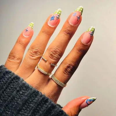 A hand with colorful nail art featuring patterns, wearing three rings