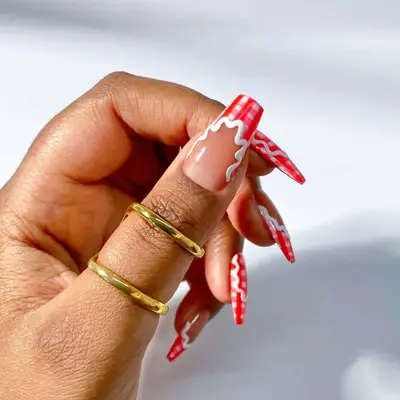 Hand with long decorated nails and gold rings