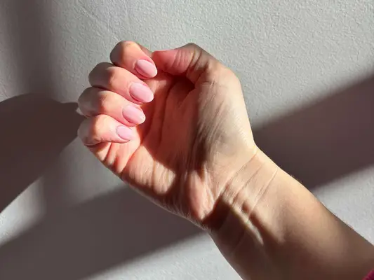 Hand with neatly manicured nails in a soft pink tone