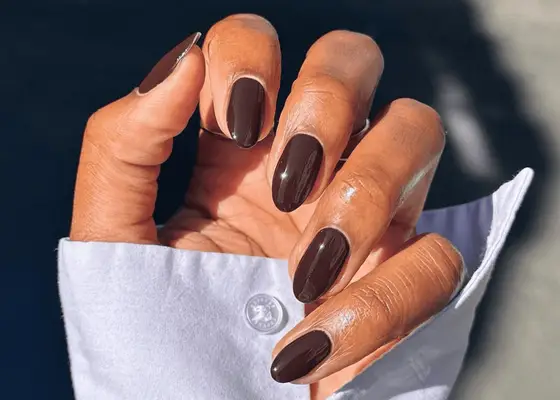 Chocolate brown nails against white button-down shirt