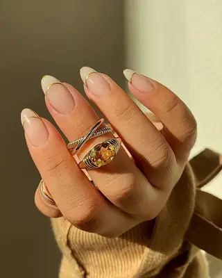 A French manicure with milky tips outlined in gold