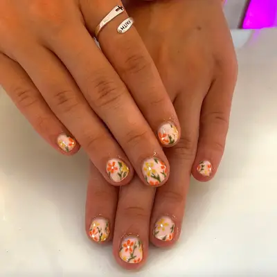 Short acrylic nails with nude base and floral design