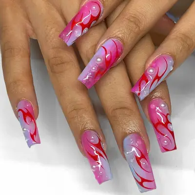 Hands displaying long decorated acrylic nails with artistic patterns