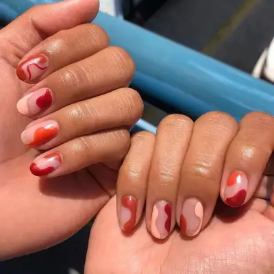 Bubble bath pink nails with rusty orange and red colored blobs.