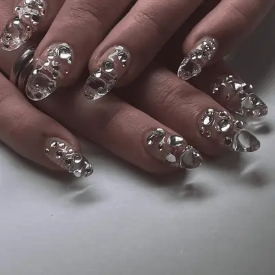 A close up of clear long nails with 3D gel blobs. 