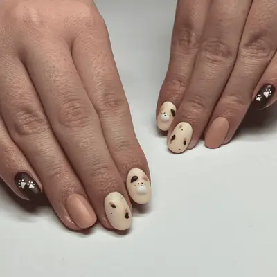  A set of brown, cream, and pink nails with cat and dot accent nails.