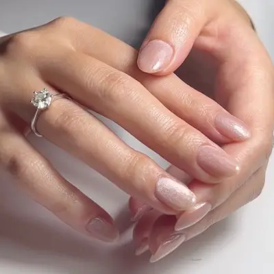 Hands showing neutral velvet nails with a silver ring on one finger