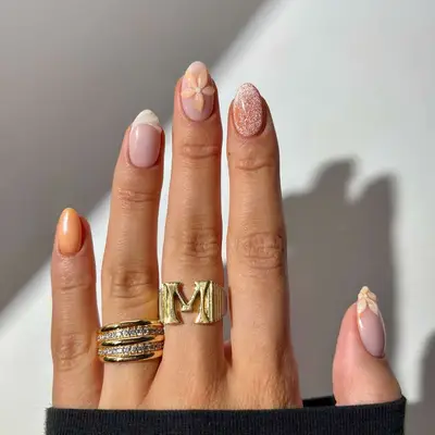 Close-up of a hand with manicured nails featuring a mix of designs and rings on the fingers