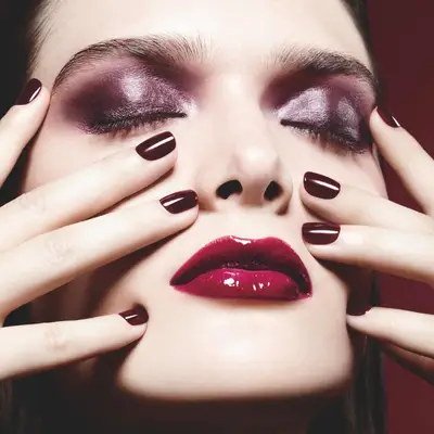 A woman wearing purple eyeshadow and Chanel Rouge Noir nail polish.