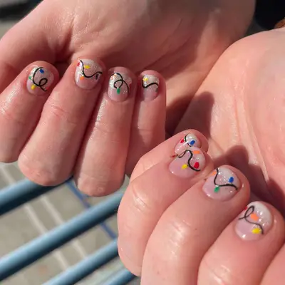 Short manicure with silver glitter and colorful holiday light string designs