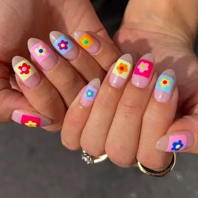 Close-up of hands with nails decorated with colorful flower designs over a light base
