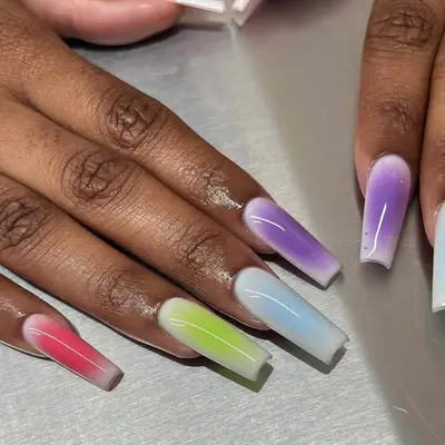Hands with long nails featuring gradient manicure in vibrant colors on each nail