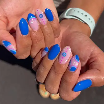 Close-up of hands displaying nail art featuring blue and pink designs with circular motifs