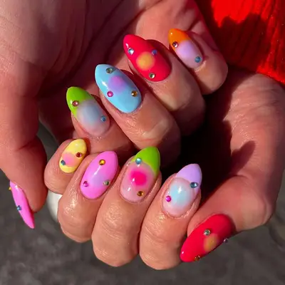 Colorful nail design with gradient patterns and gemstone accents, showcasing a creative manicure style