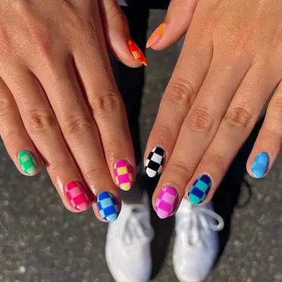 Hands displaying a checker pattern nail design in different colors