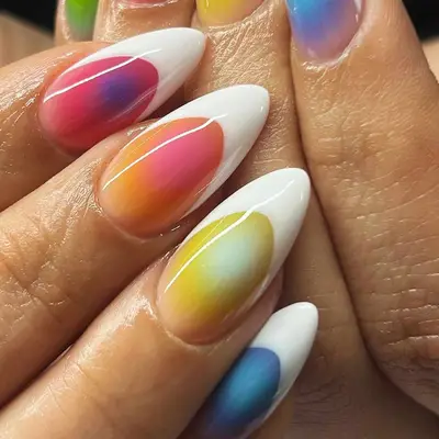 Close-up of hands with long oval-shaped nails featuring a rainbow gradient design