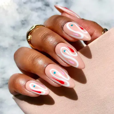 Hand with elaborate nude nail art featuring circular patterns and accents