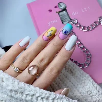 White manicure with cartoon gradient eye and lightning bold accent nails