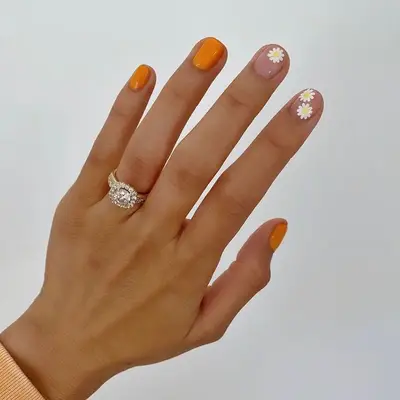 Orange manicure with daisy floral accent nails