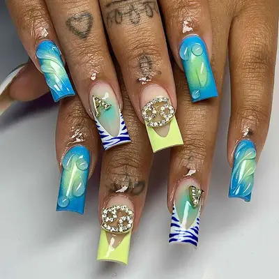 Mismatched blue and yellow manicure with tiger stripes, a Pisces gem and water droplets