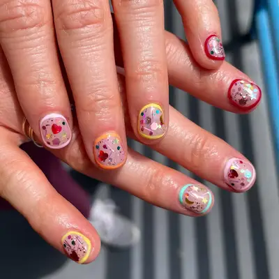 a manicure with frames around the fingers and encapsulated confetti