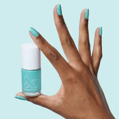 A hand with manicured nails holding a bottle of nail polish