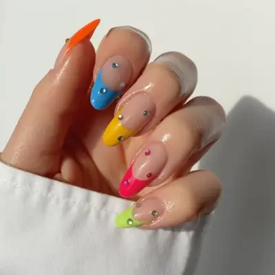 close up of nails with each french tip in different color including orange, blue, yellow, pink, green, with rhinestones on each nail corresponding to each colored tip
