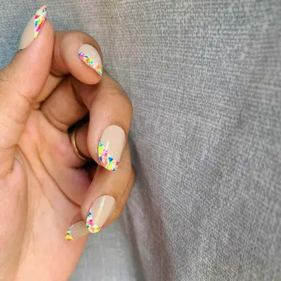 close up of nails with french tips in tie dye pattern including colors of pink, blue, orange, yellow, green