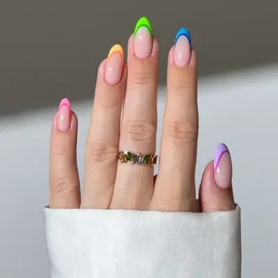 close up of nails with french tips in different colors including pink, orange, green, blue, purple, with darker color of every hue lining bottom of tip