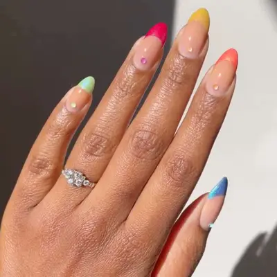 close up of nails with each one in different color for french tips including green, pink, yellow, orange, blue, with rhinestone on each nail in same color of tip