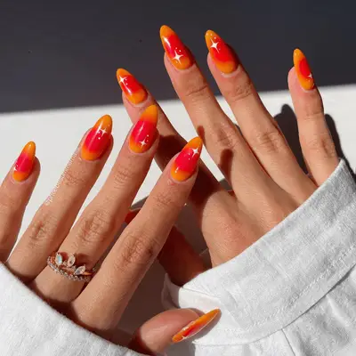 orange and yellow rounded aura nails with white star designs