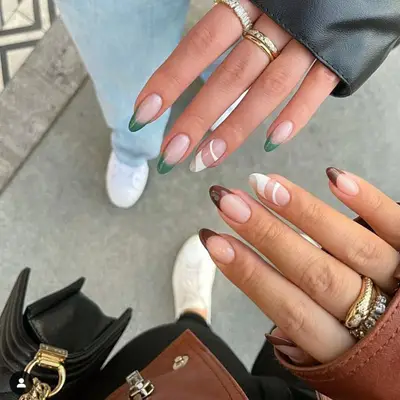 Two hands with coordinating manicures, one brown French tips and one green
