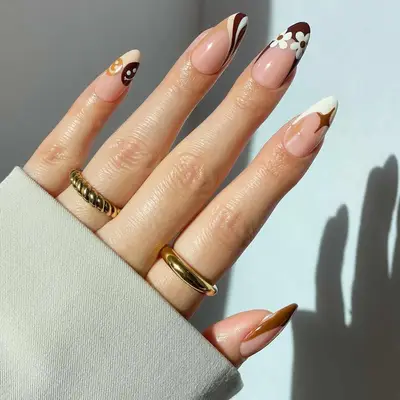 French manicure with brown, tan, and cream tips with smiley face, wave, sparkle, and flower patterns